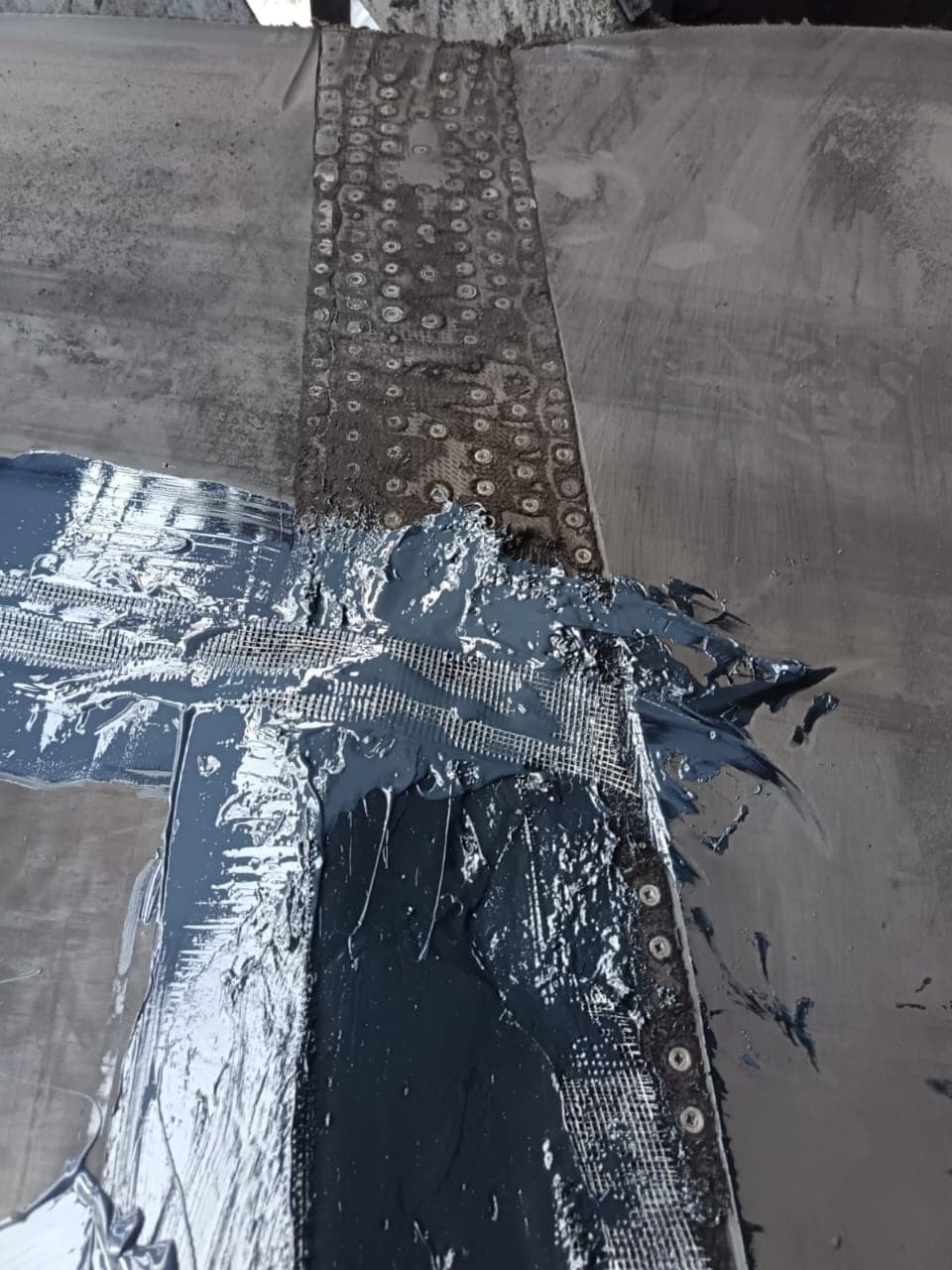 Reinforcing fabric being embedded into wet KK-Fix compound across the fastener plates of a belt splice