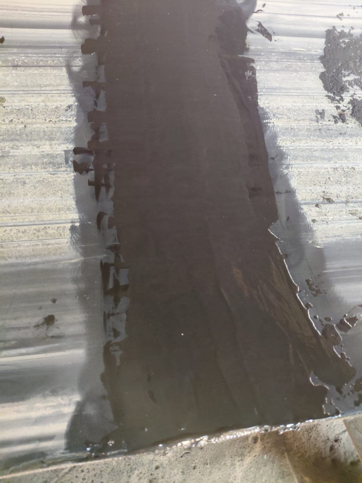 A cured KK-Fix repair covering a conveyor belt splice, forming a smooth sealed strip over the fasteners